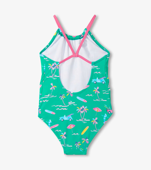 Green swimsuit with pink straps and tropical pattern on a white background