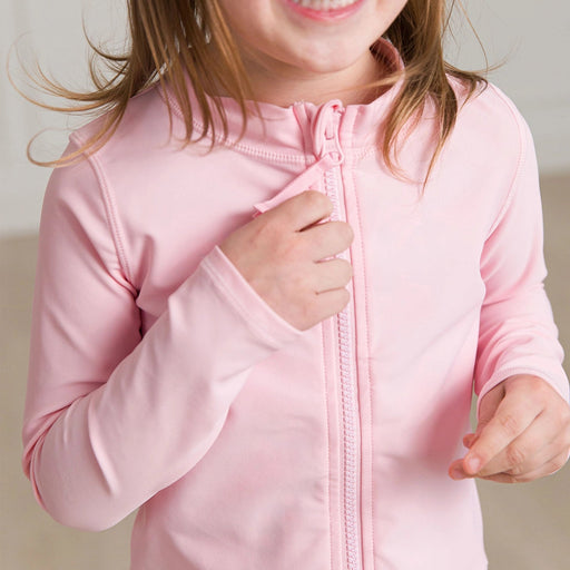 Child wearing a pink jacket with a plain background
