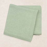 Folded green blanket on a beige background
