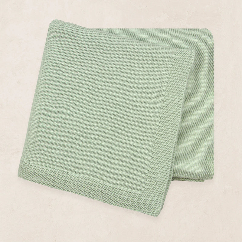Folded green blanket on a beige background