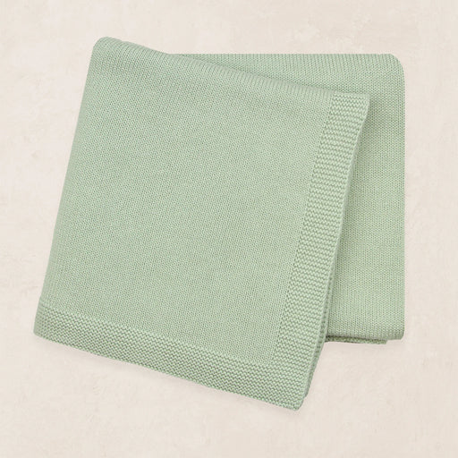 Folded green blanket on a beige background