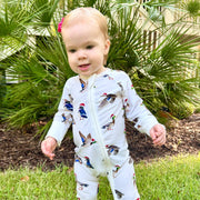 Toddler standing outdoors wearing Saltwater Swaddles Duck The Halls bamboo footie covered in festive ducks with Santa hats