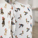 Two mannequins wearing white shirts with animal pattern, including dogs and ducks wearing santa hats, on a blurred background.