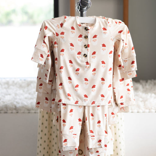 Children's pajama set with red santa patterns on a hanger against a neutral background