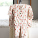 Children's pajama set with red santa patterns on a hanger against a neutral background