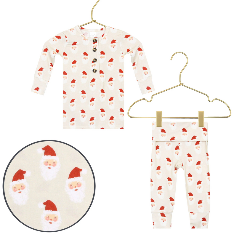 Children's pajama set with Santa Claus pattern on hangers against a white background.