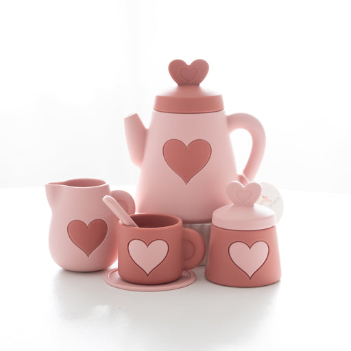Pink silicone tea set with heart designs on a white background