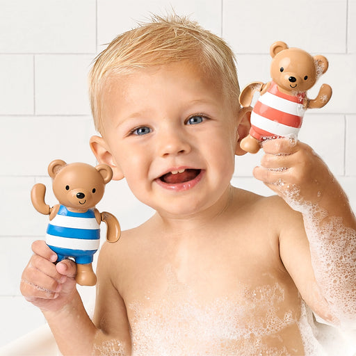 Baby holding and smiling with Silly Swimmers bath toys during bath time