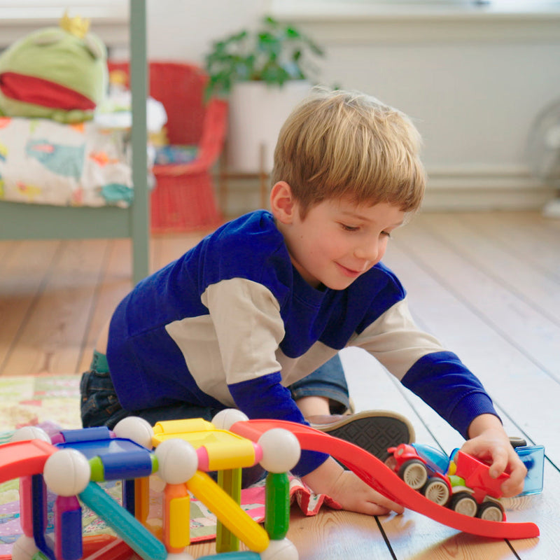 Boy building a SmartMax stunt track with magnetic bars and ramps