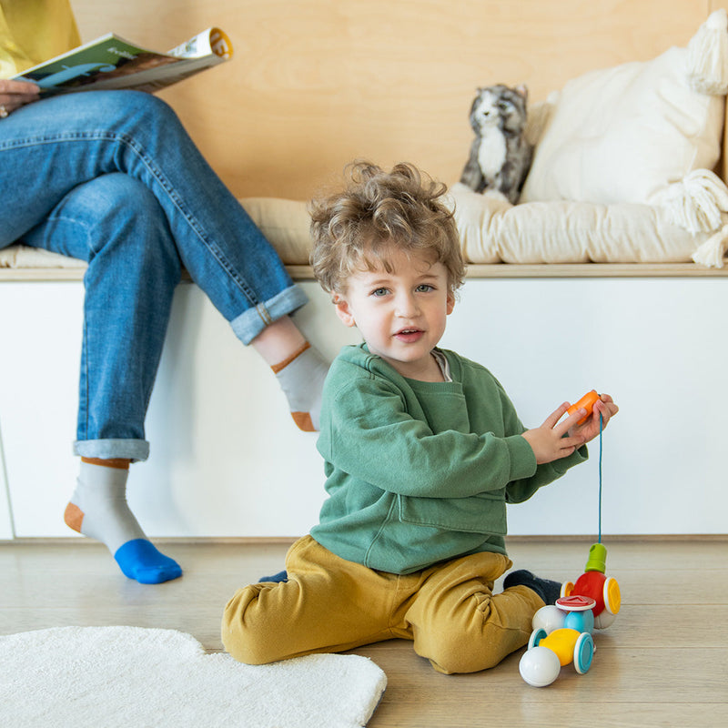 Toddler sitting on the floor pulling SmartMax My First Wobbly Cars
