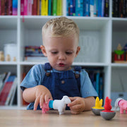 Child playing with colorful animal toys on a table in front of a bookshelf.
