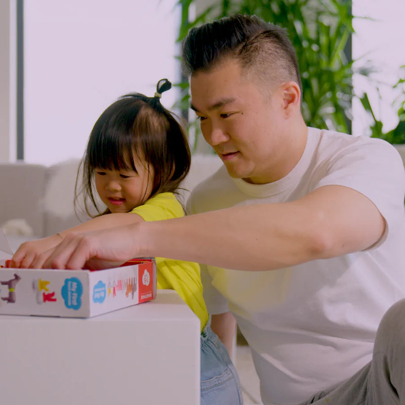 Man and young girl interacting with a toy box in a home setting