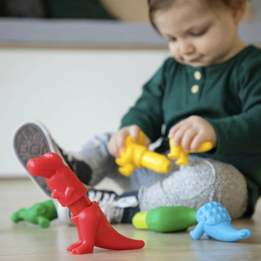 Child playing with toy dinosaurs on a wooden floor