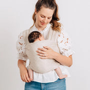 Woman holding a baby in a sling against a white background