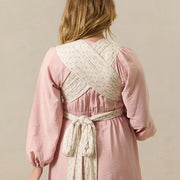 Woman wearing a pink dress with a white woven back panel against a beige background