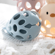 Blue textured ball and beige duck toy on a soft white surface