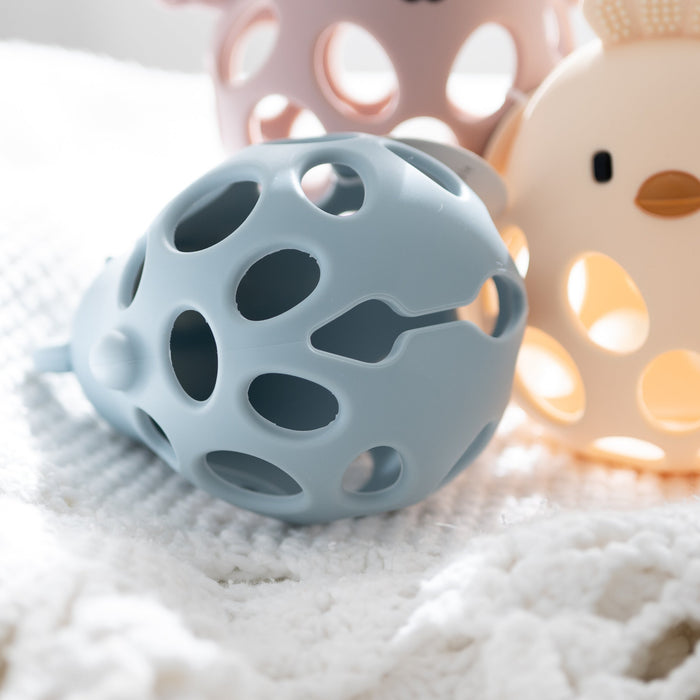 Blue textured ball and beige duck toy on a soft white surface