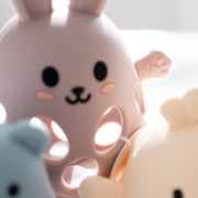 Two cute animal-shaped objects, one pink and one beige, on a light background.