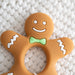 Gingerbread man teether with a green bow tie on a textured white background