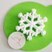White snowflake-shaped teether on a green mat with 'sugar & Maple' label.
