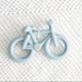 Blue bicycle-shaped teether on a textured white surface