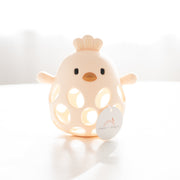 yellow silicone chick teether on a white surface with a blurred background