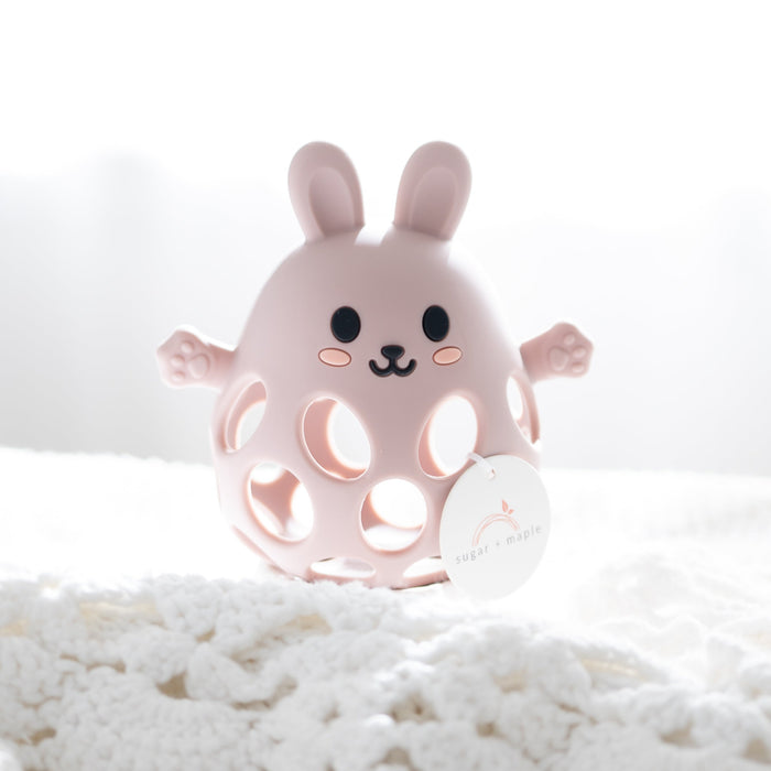 Pink rabbit-shaped teether on a white textured surface