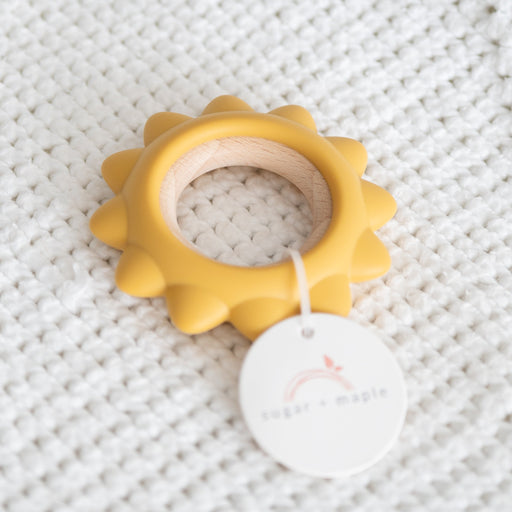 Yellow teething ring with a white tag on a textured gray background