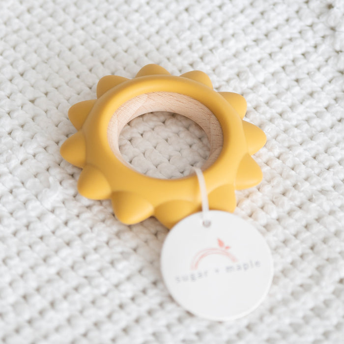 Yellow teething ring with a white tag on a textured gray background
