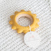 Yellow teething ring with a white tag on a textured gray background