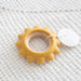 Yellow sun-shaped teething ring on a white textured surface