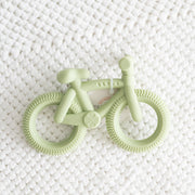 Light green bicycle-shaped teether on a white textured background