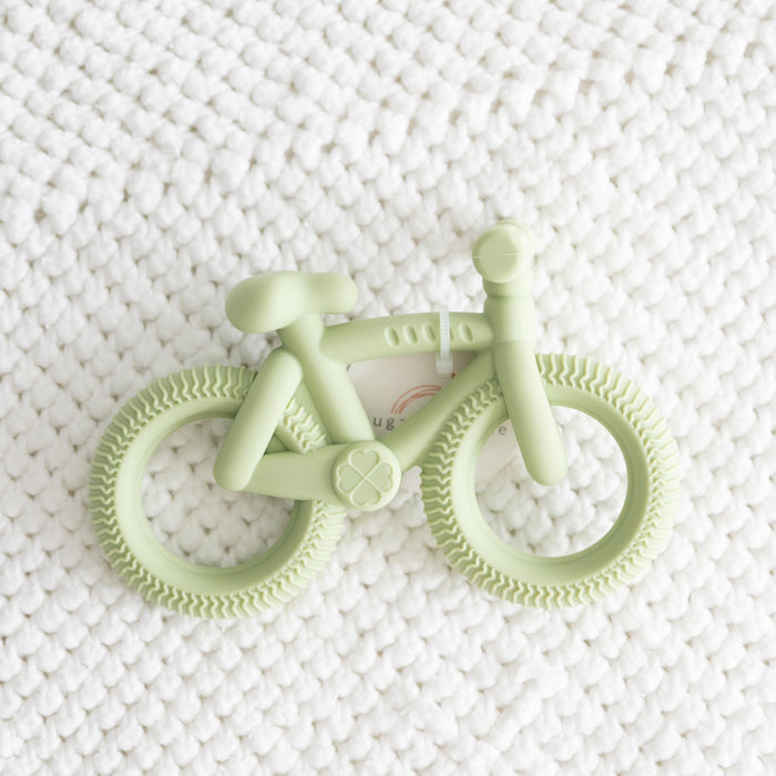 Light green bicycle-shaped teether on a white textured background
