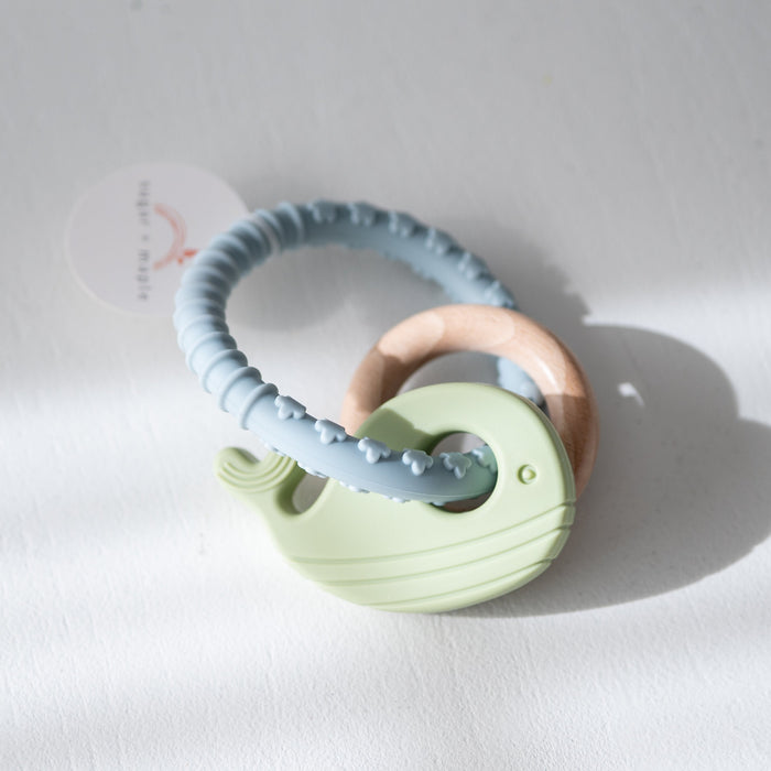 Baby teether with green whale and wooden ring  on a white background