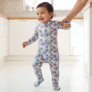 Baby in a floral onesie being held by an adult in a bright room.