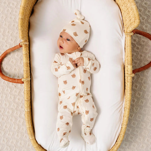 Newborn in a Moses basket wearing the Lou Lou & Co Teddy bear zipper footie and matching knot hat