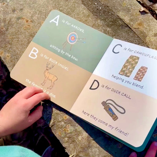 Children's alphabet book open on a stone surface