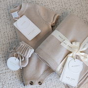 Tan baby outfit with matching booties and blanket on a textured surface with 'LOU LOU' branding.