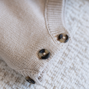 Close-up of a beige knitted fabric with buttons on a textured surface