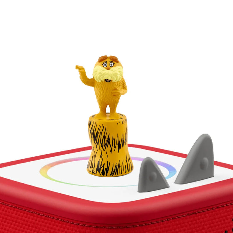 A red square electronic device with a white top panel, featuring a small yellow cartoon lion figure standing on a textured yellow pedestal and two gray shark-shaped elements on the surface, shown against a plain white background.
