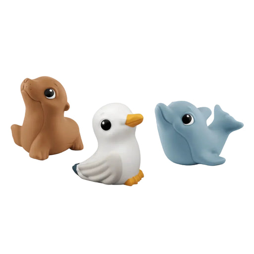 Three small soft toy animals on a plain white background: a brown seal on the left, a white seagull in the center, and a light blue dolphin on the right.