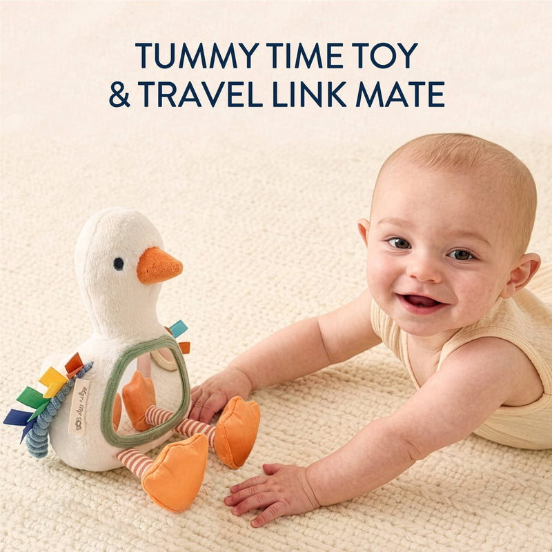 Baby playing with a toy duck on a textured surface, with text 'Tummy Time Toy & Travel Link Mate' above.