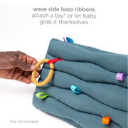 Close-up of wave-textured fabric with colorful ribbon loops on the Ubbi baby mirror toy