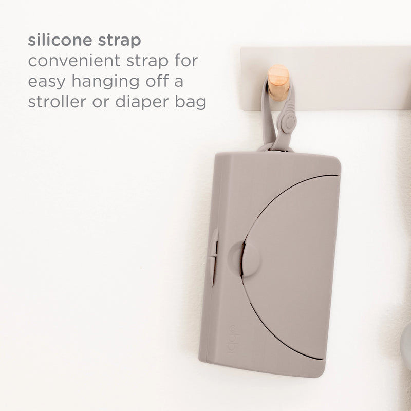 Ubbi On-the-Go Wipes Dispenser hanging from a hook by its silicone strap, which attaches to a stroller or diaper bag