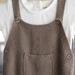 Brown knitted overall with buttons on a white background
