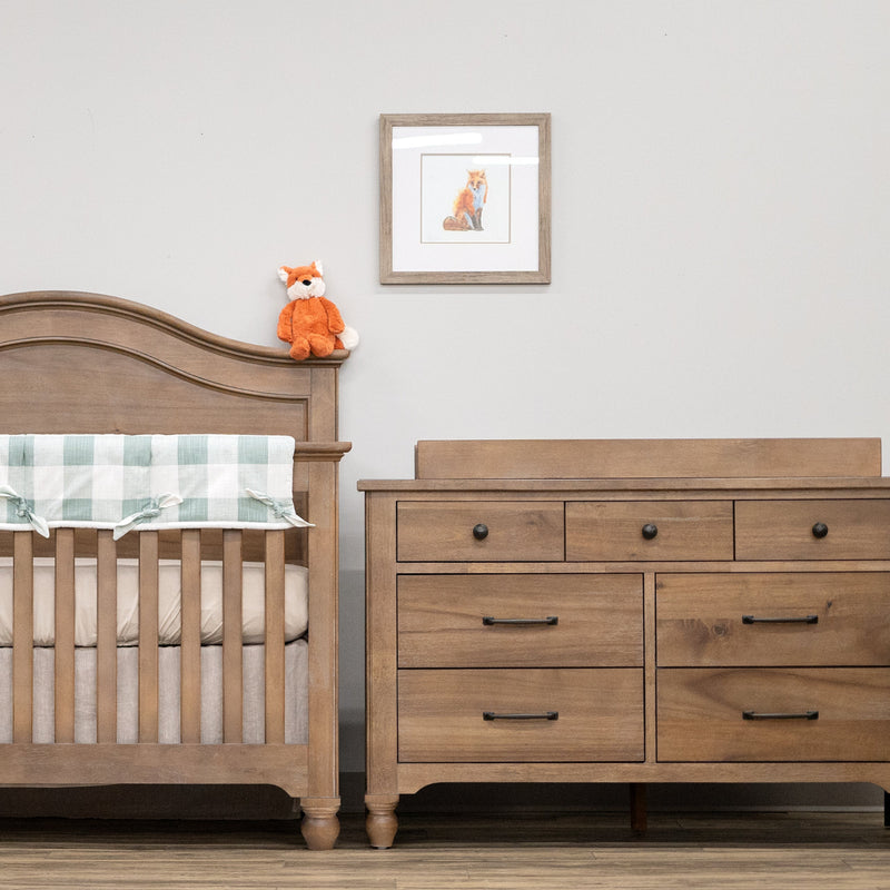 Wooden crib with checkered blanket and dresser in a nursery setting