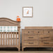 Wooden crib with checkered blanket and dresser in a nursery setting