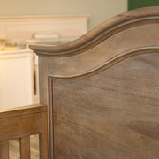 Wooden headboard of an arch top crib in a baby nursery