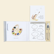 Open book with illustrations of a paint palette and cloud shapes on a beige background