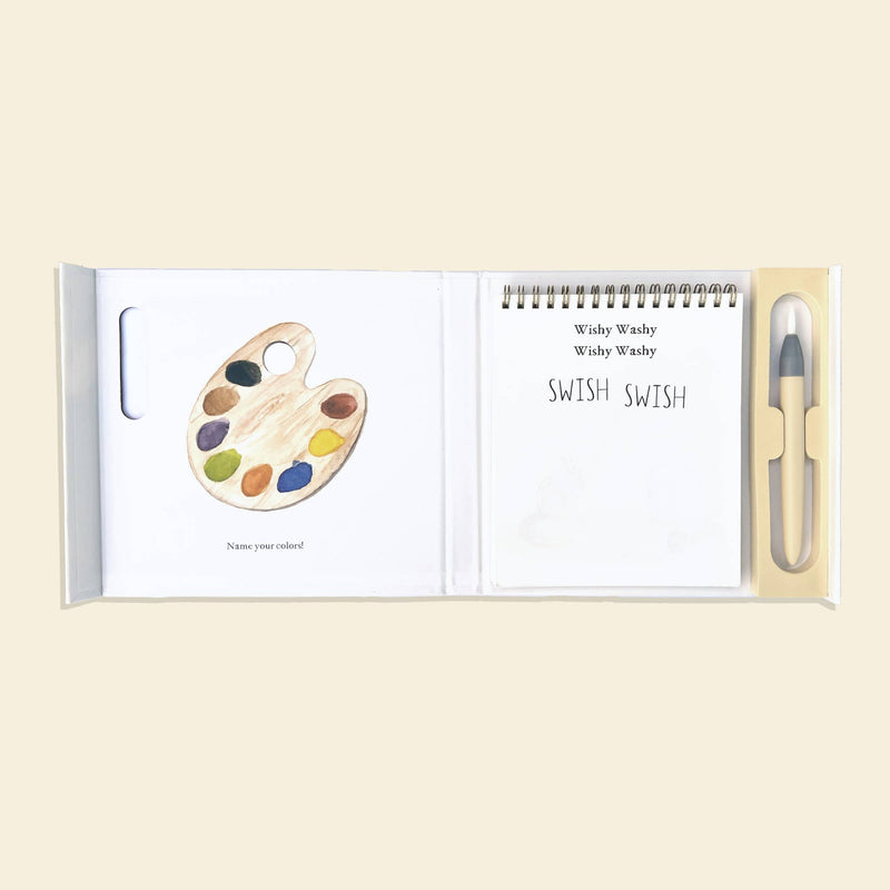 Open book with paint palette illustration and pen on beige background